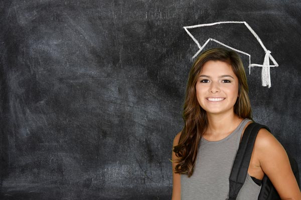 Woman in front of blackboard with a drawing of a graduation cap.